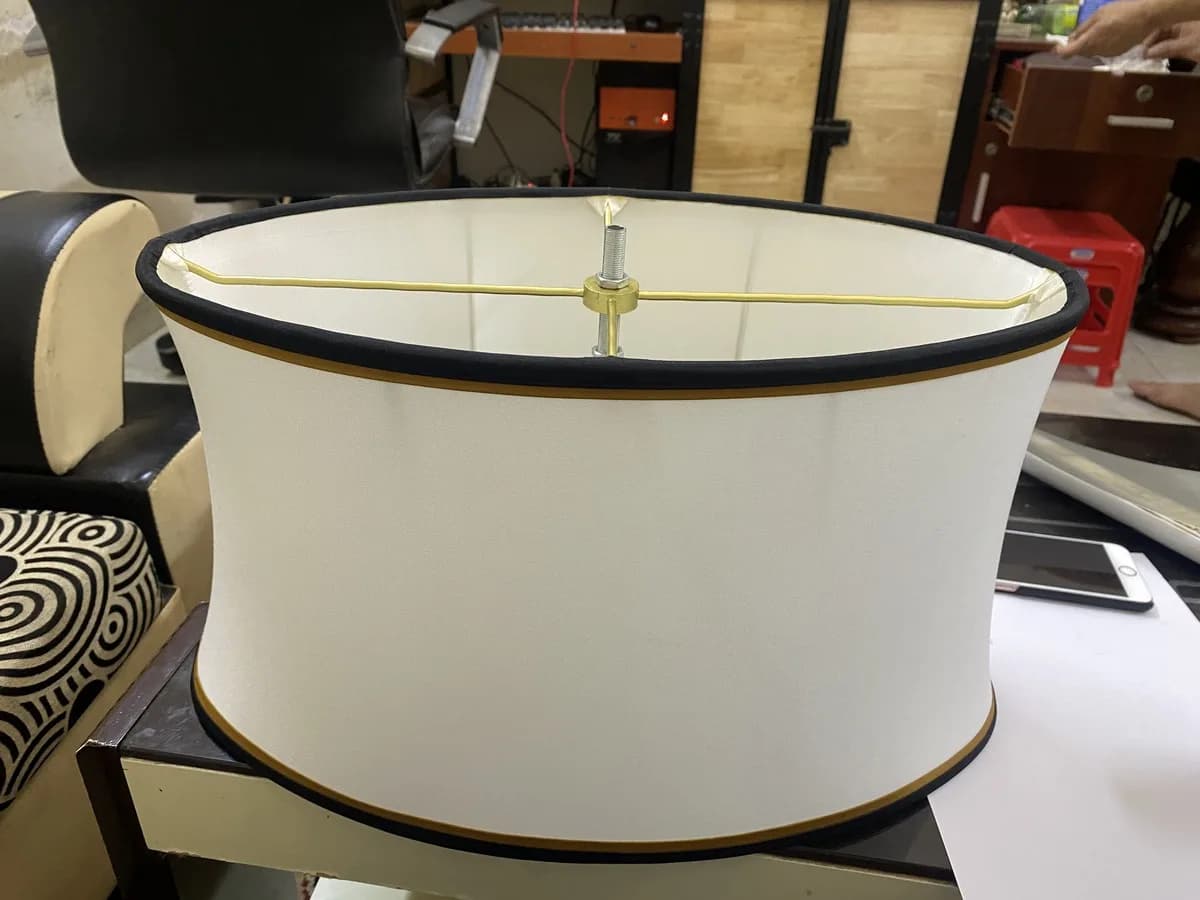 An oval fabric shade with a gold-painted trim, delivered by KAHA