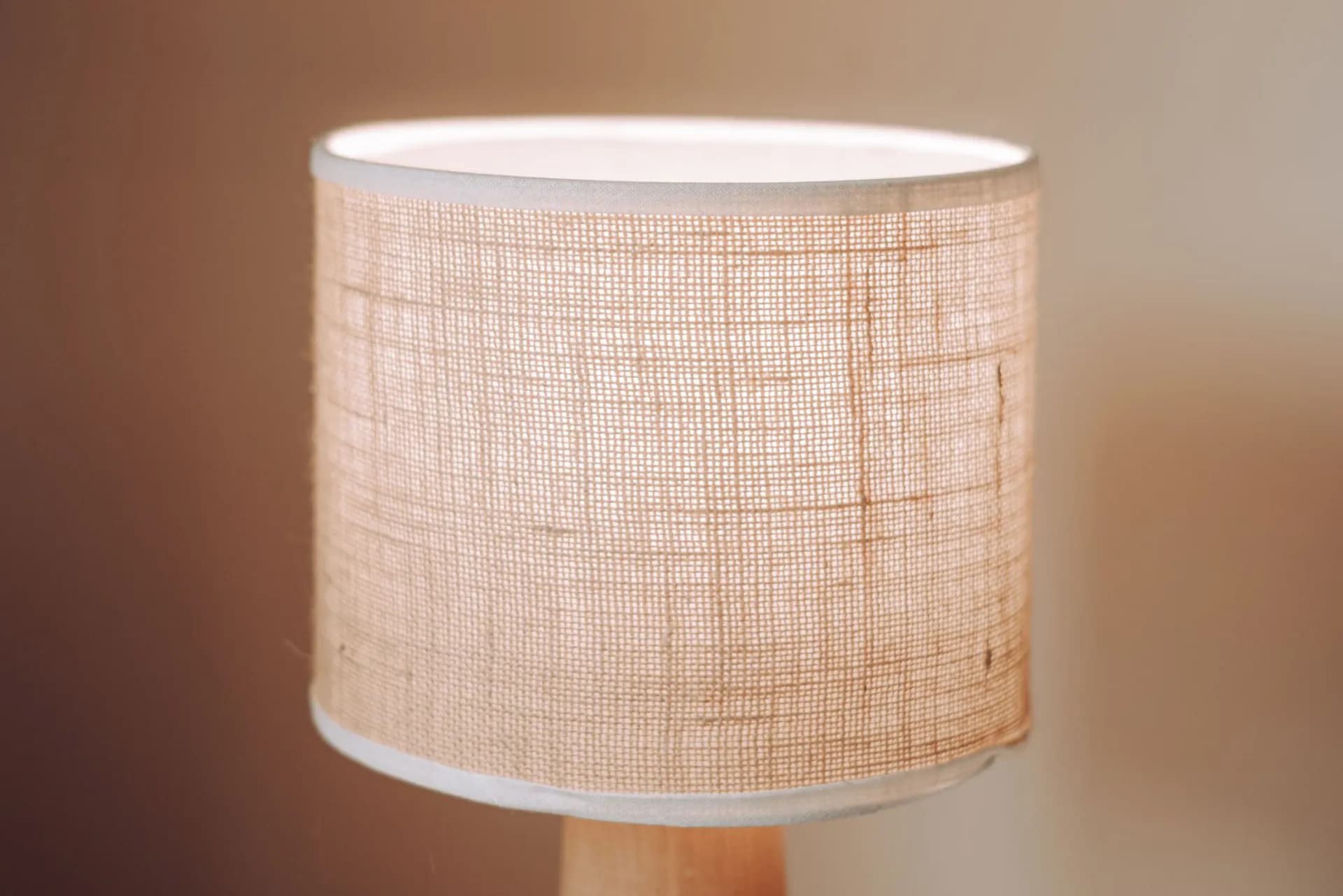 Close-up of light passing through a fabric shade's weave, showing how the cloth diffuses the bulb behind it