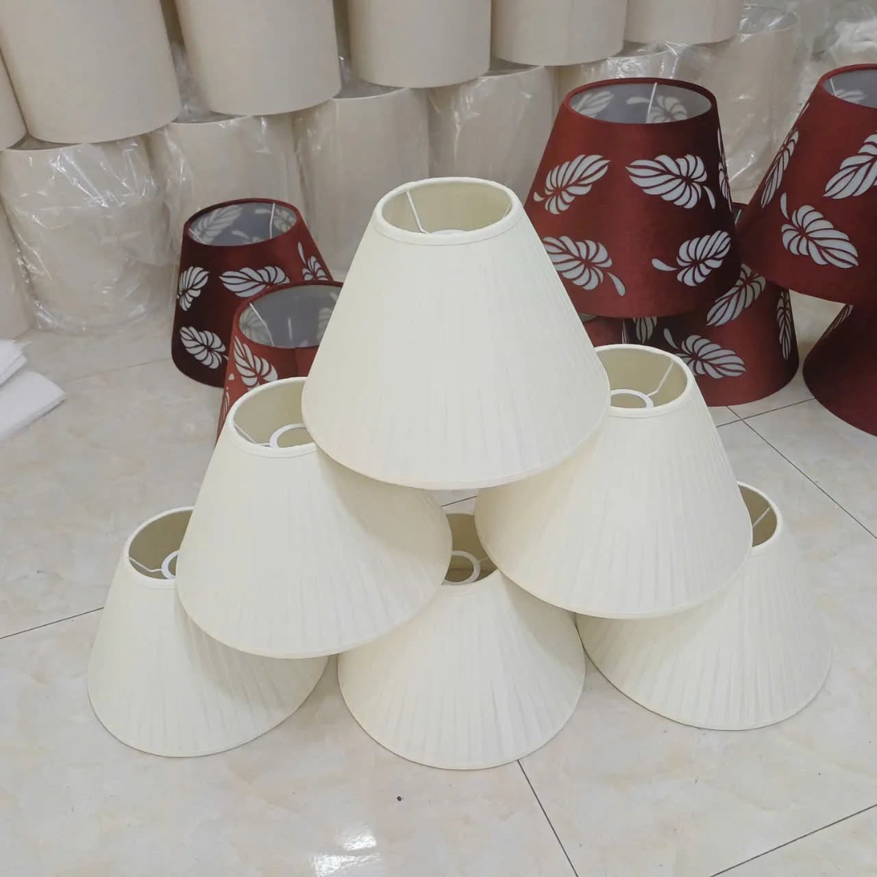 Stacked pleated fabric lamp shades stored at KAHA's workshop, awaiting quality check