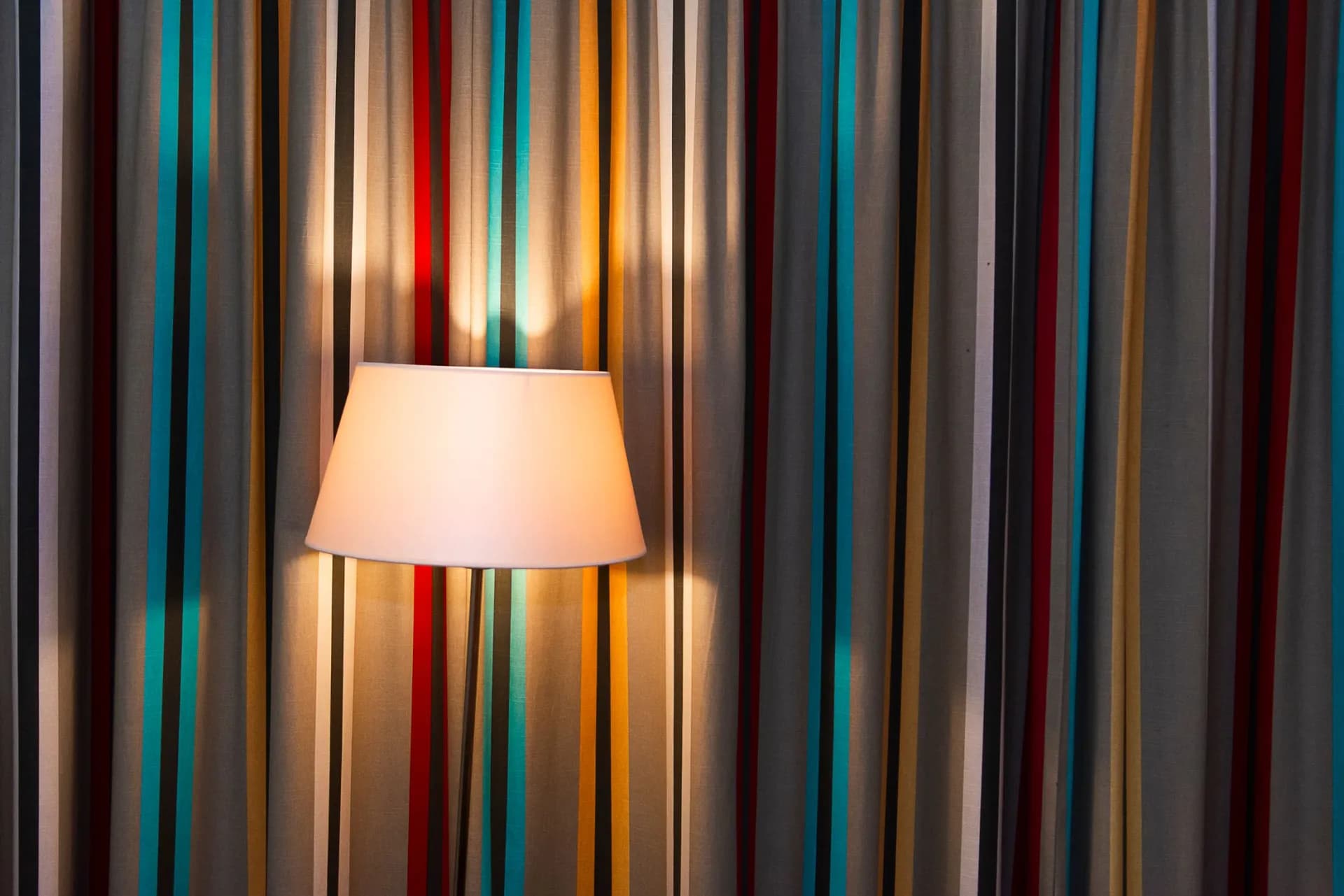 A range of coloured fabric swatches used for KAHA lamp shades, laid out at the workshop