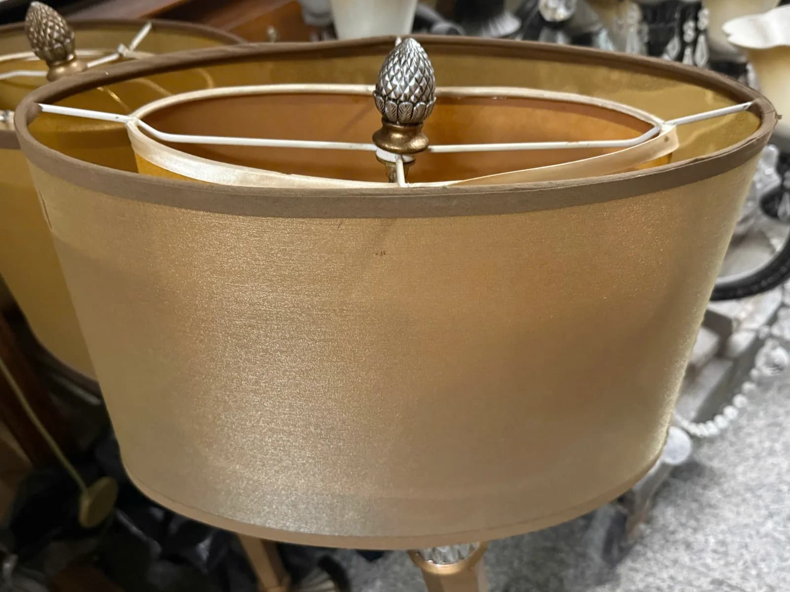 Chụp đèn oval bọc vải vàng ánh kim, nhìn thấy khung, lớp lót bên trong và núm trang trí phía trên