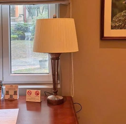 Chụp đèn xếp ly màu kem trên đèn bàn chân kim loại cạnh cửa sổ