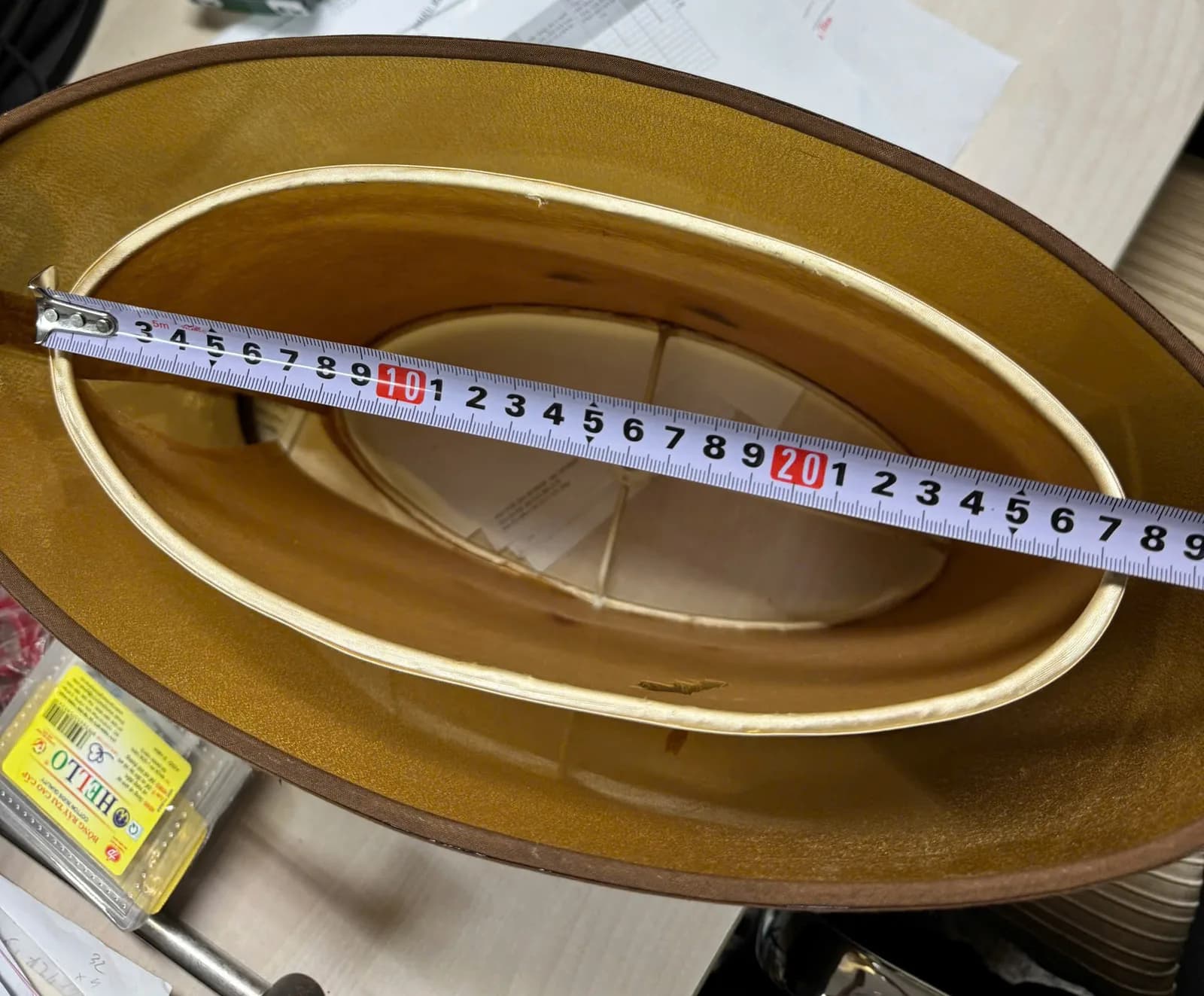 Thước dây đo trục dài của chụp đèn oval nhìn từ trên xuống, thấy lớp lót vàng bên trong