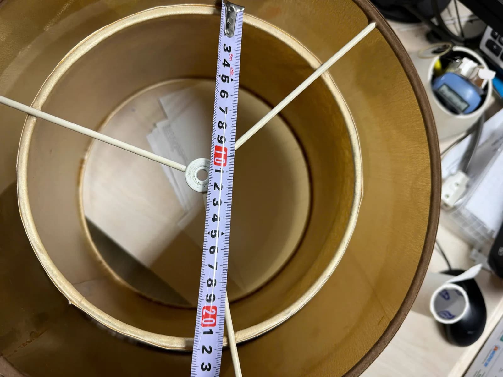 Thước dây đo đường kính chụp đèn trụ vàng nhìn từ trên xuống, thấy vòng đỡ ba chân và lớp lót