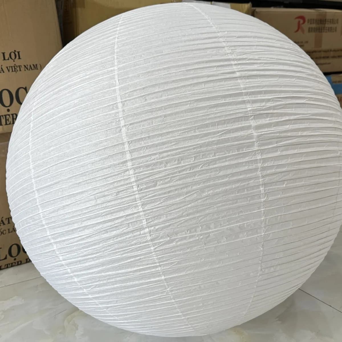 A large ivory wabi-sabi fabric lamp with a hand-pleated surface, made at KAHA's workshop