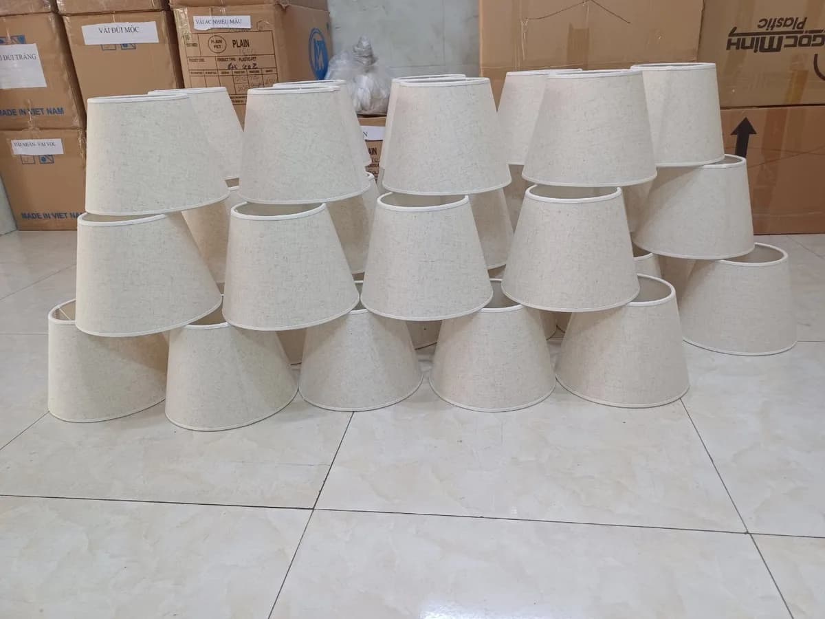 Chụp đèn vải nón màu be xếp tháp cạnh khu đóng gói của xưởng KAHA